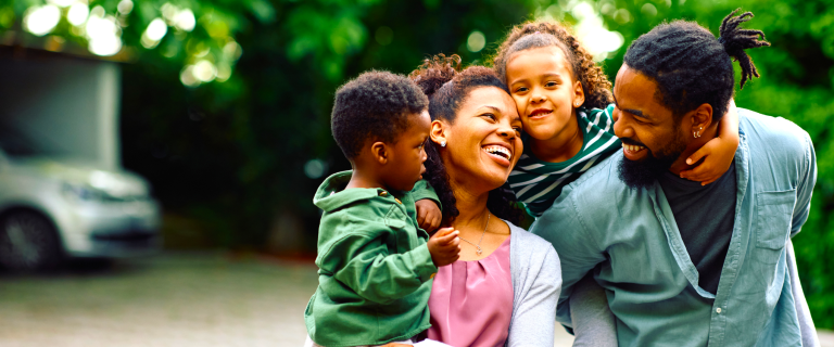 family smiling in driveway