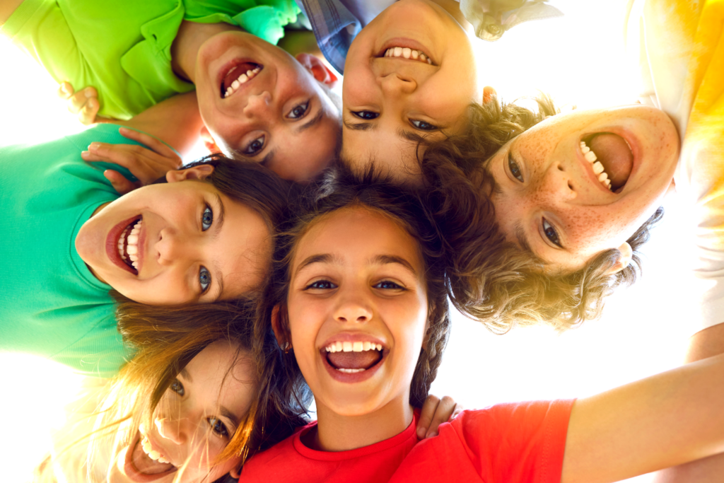 Children in bright colors with arms wrapped around each other
