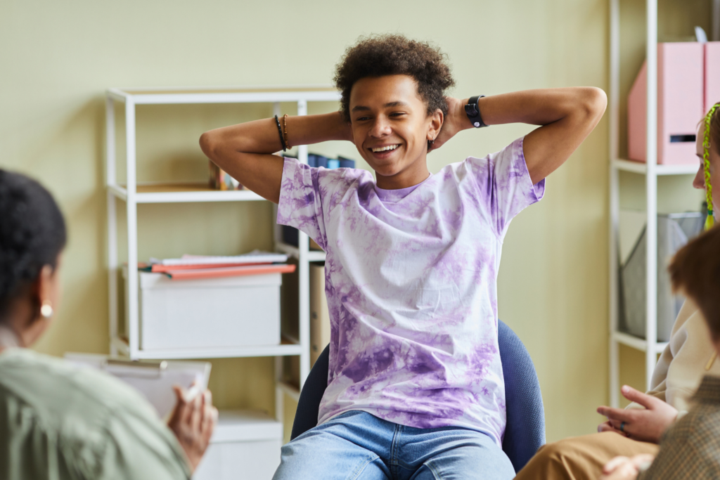 Teenager with purple tie dye shirt and hands behind head