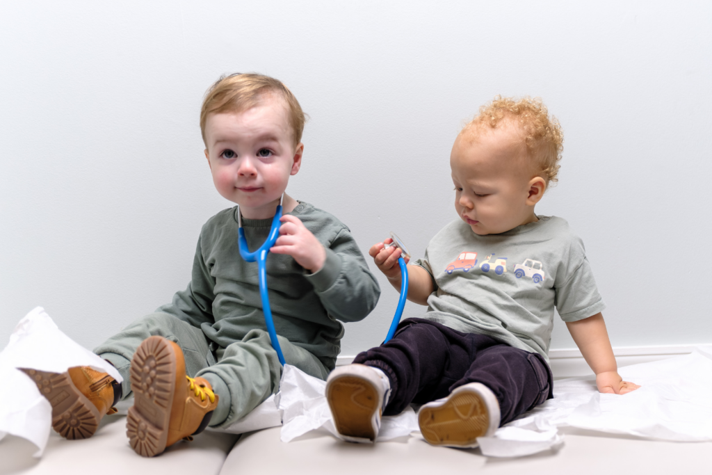 Two toddlers sitting on medical table