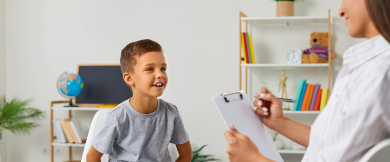 Child sitting across from female counselor with clipboard in hand