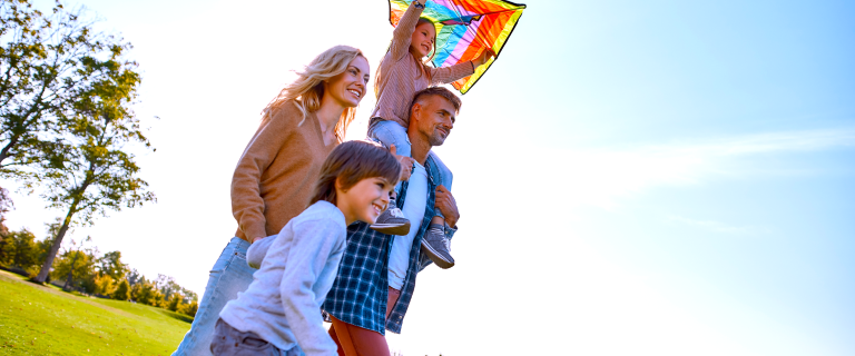 Family outside with child on shoulders and kite in hands